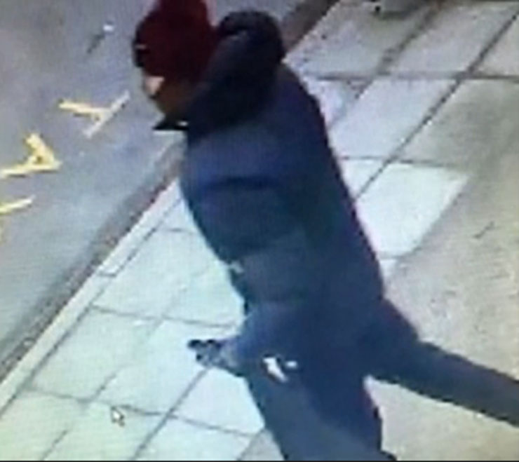 Φοράει σκούρο μπουφάν, σκούφο και κρατάει μαύρο σακίδιο